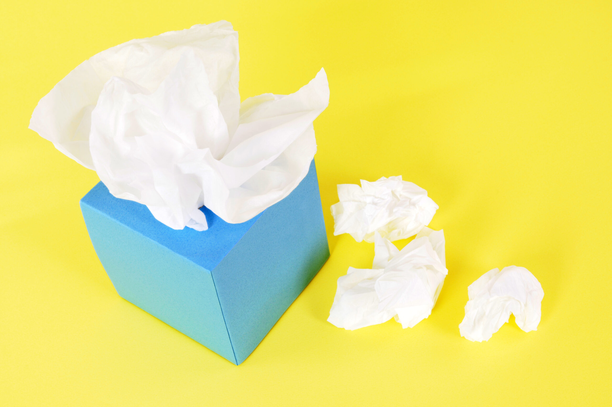 Kleenex style tissues in blank blue box on a yellow background.